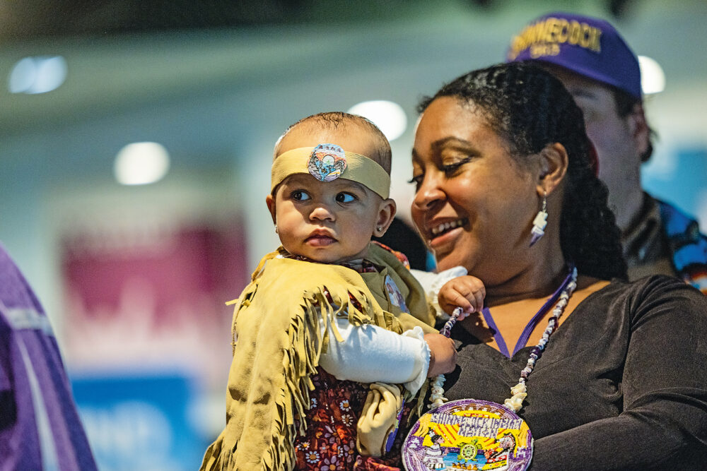 Indigenous infant and mother in traditional ceremonial attire.